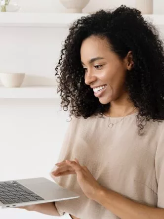 A lady smiling and clicking a button on her laptop